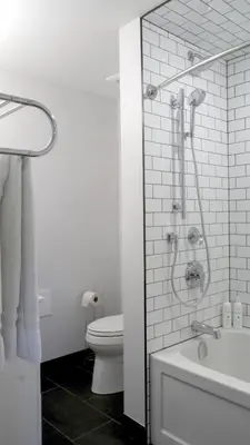 a white bathroom with a shower and a toilet at South Landing Inn in Niagara on the Lake