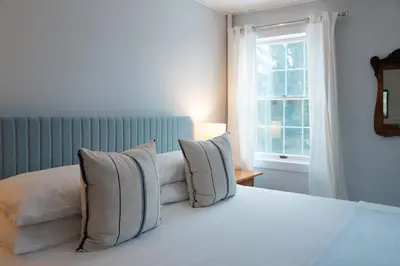 a bedroom with a bed with pillows and a window at South Landing Inn in Niagara on the Lake