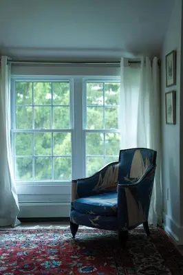 a blue chair in a room with a window at South Landing Inn in Niagara on the Lake