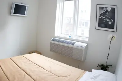 a bedroom with a bed and a window with a air conditioner at The Rex Hotel Jazz & Blues Bar in Toronto
