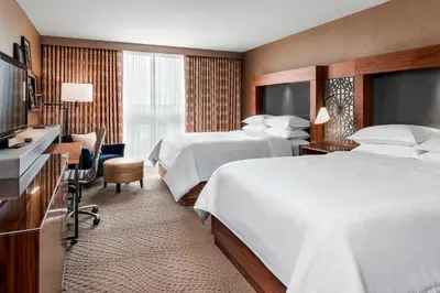 a hotel room with two beds and a desk at Sheraton Toronto Airport Hotel & Conference Centre in Toronto