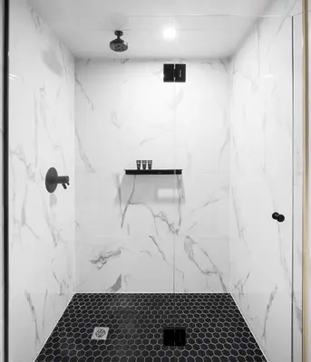 a bathroom with a shower with white marble walls at The Broadview Hotel in Toronto