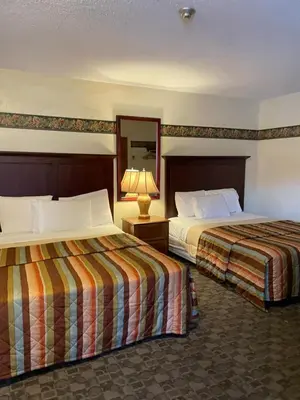 a hotel room with two beds and a lamp at Scottish Inn Near the Falls and Casino in Niagara Falls