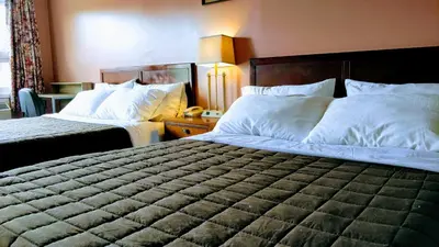 a hotel room with two beds with white pillows at Kings Inn Midland in Midland
