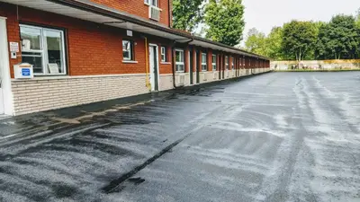 an empty parking lot next to a brick building at Kings Inn Midland in Midland