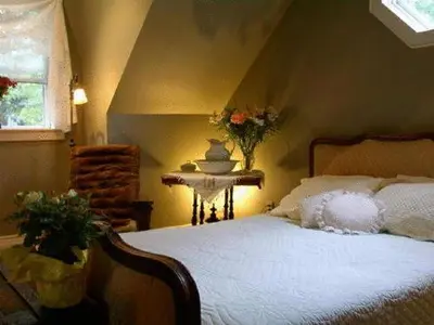 a bedroom with a bed and a table and a window at Antique Slumber Old Town Bed & Breakfast in Niagara on the Lake