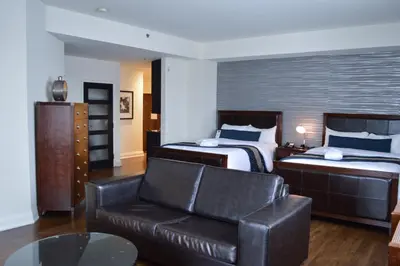 a hotel room with two beds and a leather couch at Sterling Inn & Spa in Niagara Falls