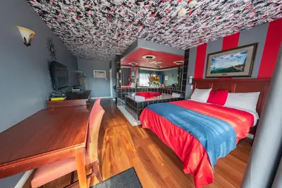 a bedroom with a red and blue bed and a desk at Villager Lodge Niagara Falls in Niagara Falls