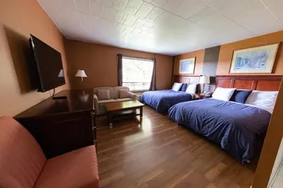 a hotel room with two beds and a flat screen tv at Villager Lodge Niagara Falls in Niagara Falls