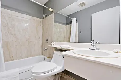 a bathroom with a toilet and a sink and a bath tub at Niagara Lodge & Suites in Niagara Falls
