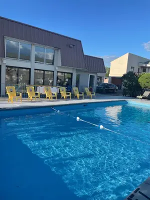 a swimming pool with blue water and yellow chairs at Niagara Lodge & Suites in Niagara Falls