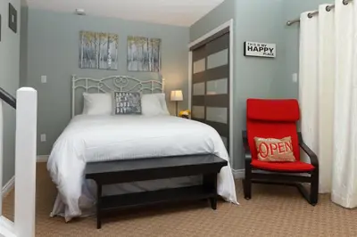 a bedroom with a bed and a red chair at Mountain Side Condo Loft at The Blue Mountains in Blue Mountains