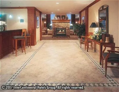 a living room with a fireplace and a table and chairs at Staybridge Suites Oakville Burlington by IHG in Oakville