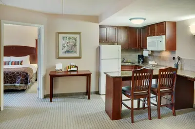 a kitchen with a refrigerator and a table and chairs at Staybridge Suites Oakville Burlington by IHG in Oakville