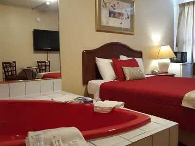 a hotel room with a red bath tub and a bed at Niagara Inn & Suites in Niagara Falls
