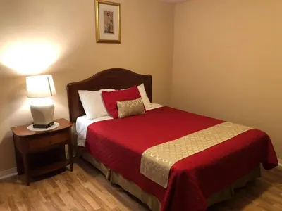 a bedroom with a bed with a red blanket and a lamp at Niagara Inn & Suites in Niagara Falls