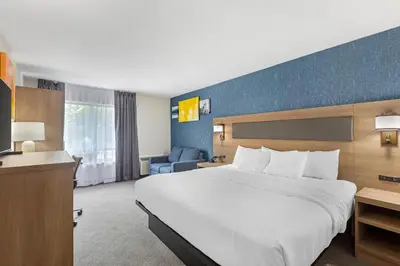 a hotel room with a large bed and a blue wall at Comfort Inn in St. Catharines