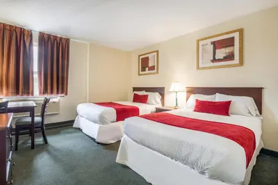 a hotel room with two beds and a desk at Knights Inn Orillia in Orillia