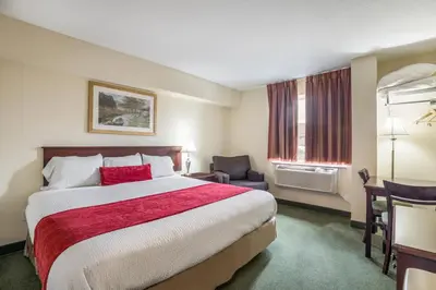 a hotel room with a bed and a chair at Knights Inn Orillia in Orillia