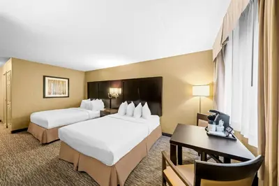 a hotel room with two beds and a desk at Best Western Plus Mariposa Inn & Conference Centre in Orillia