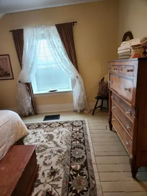 a bedroom with a bed and a dresser and a window at Stone Carriage House in Picton