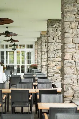 a restaurant with tables and chairs and a stone wall at Windermere House in Windermere