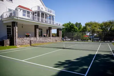 a tennis court in front of a house at Windermere House in Windermere