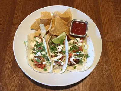 a white plate with two tacos and chips on a table at Holiday Inn - Mississauga Toronto West by IHG in Mississauga