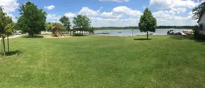 a large green yard with a playground and a lake at Pigeon Hollow Park Cottages in Bobcaygeon