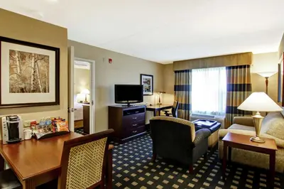 a hotel room with a desk and a living room at Homewood Suites by Hilton Toronto Airport Corporate Centre in Toronto