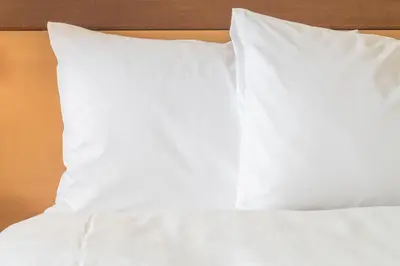a bed with white sheets and pillows on it at Holiday Inn Burlington Conference Centre by IHG in Burlington