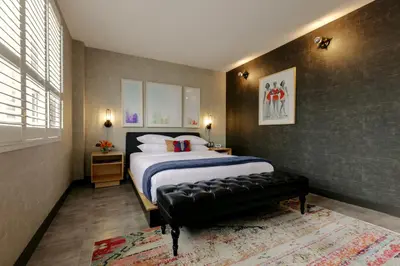 a bedroom with a large bed and a black leather bench at The Anndore House, part of JDV by Hyatt in Toronto