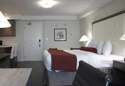 a hotel room with a large bed and a desk at Admiral Inn Mississauga in Mississauga