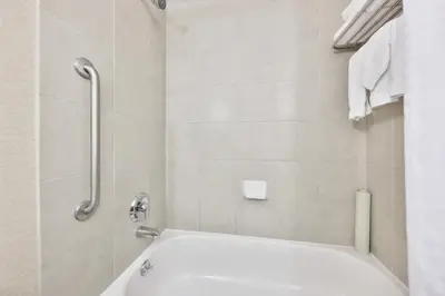 a white bathroom with a tub and a shower at Admiral Inn Mississauga in Mississauga