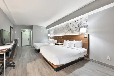 a hotel room with two beds and a desk at Admiral Inn Mississauga in Mississauga