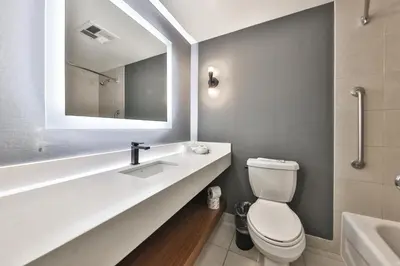 a bathroom with a toilet and a sink and a mirror at Admiral Inn Mississauga in Mississauga