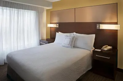 a hotel room with a large bed with white pillows at Cambridge Suites Mississauga in Mississauga