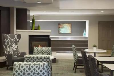 a lobby with a fireplace and chairs and a table at Cambridge Suites Mississauga in Mississauga