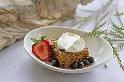 a plate with a piece of cake with whipped cream and berries at Briars Resort and Spa in Georgina