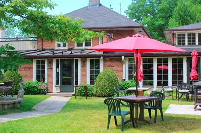 a table with a red umbrella in front of a house at Briars Resort and Spa in Georgina