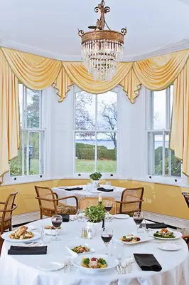a dining room with white tables and a chandelier at Briars Resort and Spa in Georgina