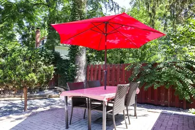 a table with a red umbrella on a patio at Addison House License# 004-2025 in Niagara on the Lake