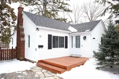a white house with a wooden deck in the snow at Addison House License# 004-2025 in Niagara on the Lake