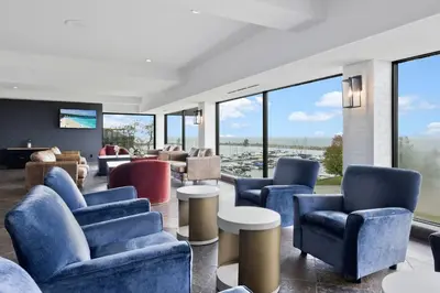 a lobby with blue chairs and tables and windows at The Jordan Hotel Ramada by Wyndham in Jordan