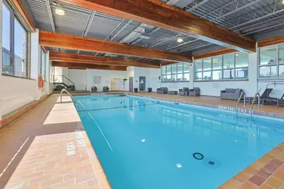 a large indoor swimming pool with blue water at The Jordan Hotel Ramada by Wyndham in Jordan