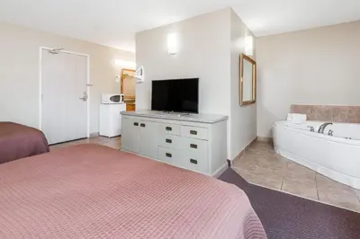 a bedroom with a bed and a tub and a tv at London Travel Inn in London
