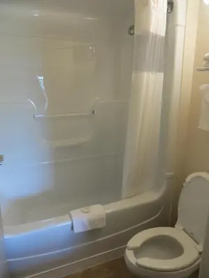 a bathroom with a toilet and a tub and a shower at London Travel Inn in London