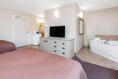 a bedroom with a bed and a tub and a tv at London Travel Inn in London