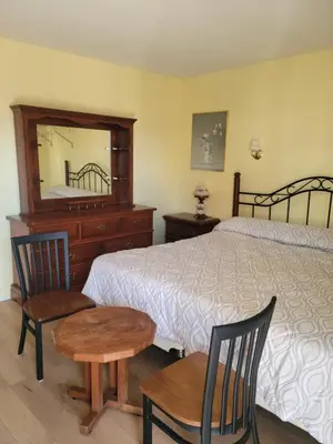a bedroom with a bed and two chairs and a mirror at Olympia Motel in Niagara Falls