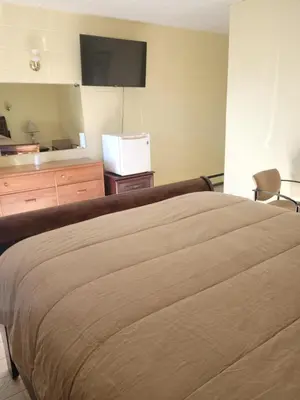 a bedroom with a bed and a flat screen tv at Olympia Motel in Niagara Falls